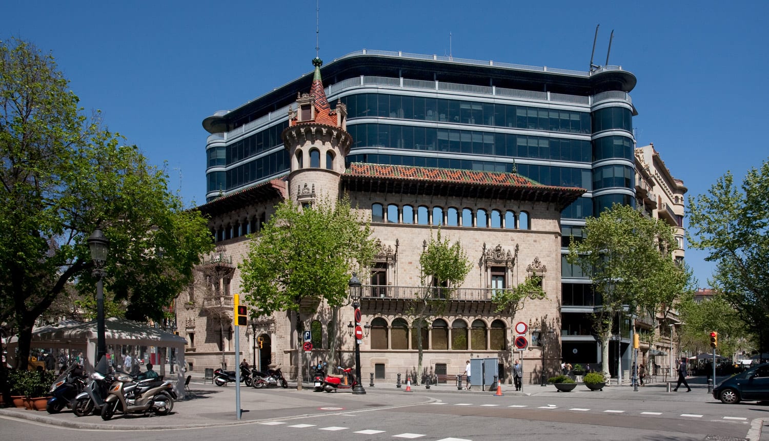 Edifici històric de diverses plantes amb façana de pedra i maó, arcs a la planta baixa i balcó metàl·lic.