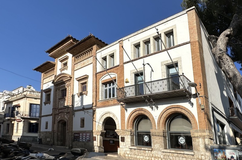 Edifici històric Casino Prado  modernista amb torre i façana de pedra davant d’un edifici modern de vidre.