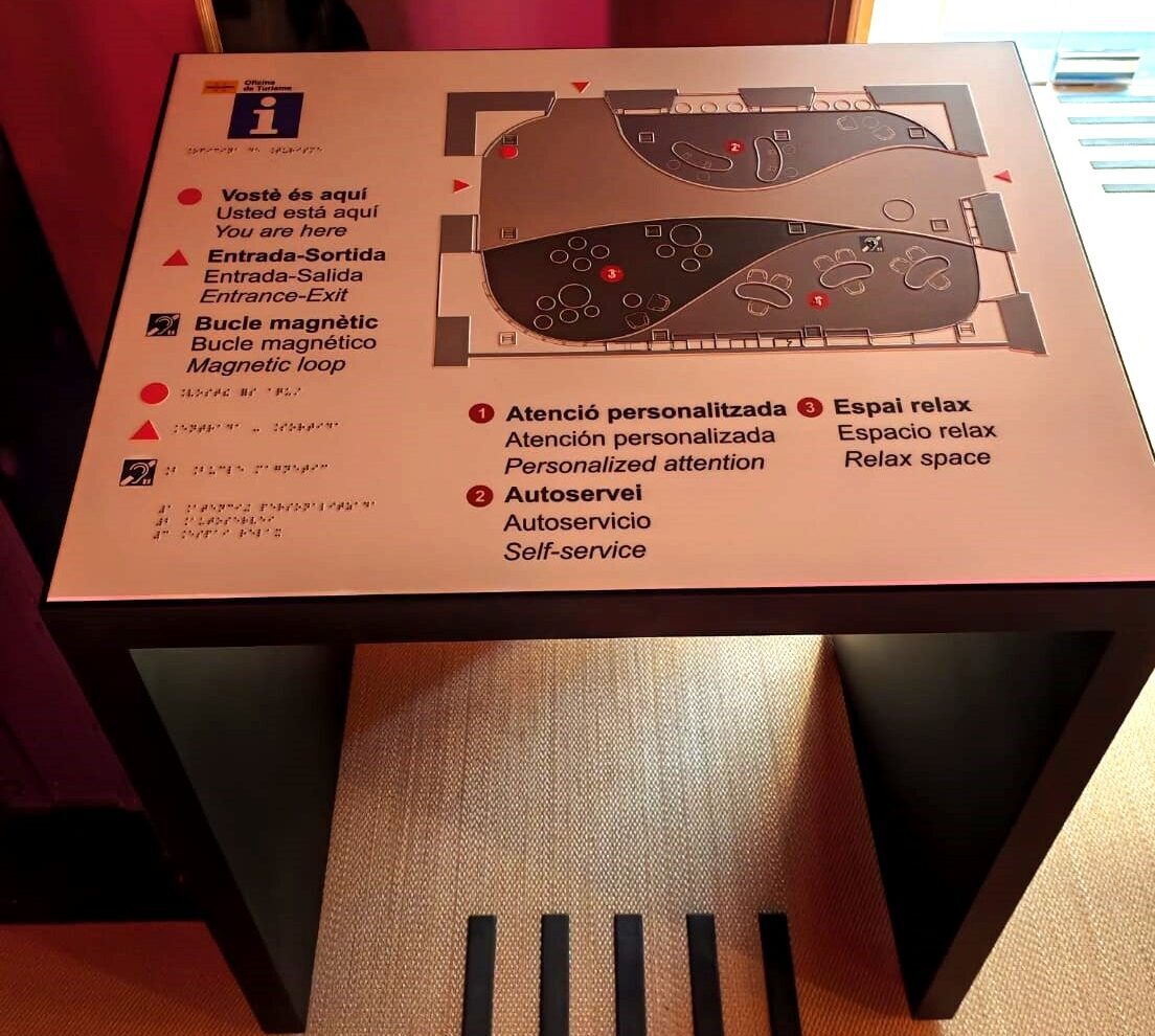 Faristol amb plafó informatiu en català, castellà i anglès, amb text en relleu i Braille, pictogrames (vostè és aquí, entrada-sortida, bucle magnètic) i un plànol tàctil de l'espai.